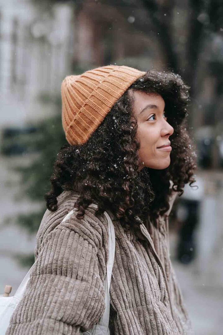 Girl protecting her hair in winter with a woolen hat.