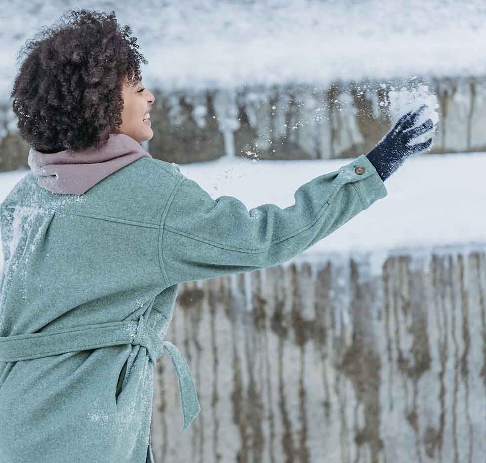 Girl with natural hair in winter throwing snow to show how to protect hair in winter